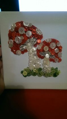 the button art is made with buttons and glass beads on white paper, which looks like an acrylic mushroom