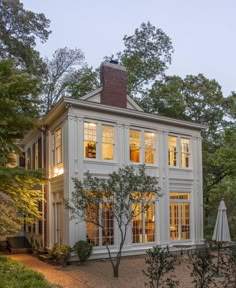 a large white house sitting in the middle of a forest