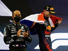 two men standing next to each other on top of a race track wearing face masks