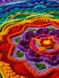 a multicolored crocheted blanket with a flower on it's center