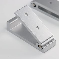 two metal brackets on a white surface, one is open and the other is closed