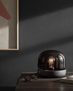 a table lamp sitting on top of a wooden table next to a clock and other items