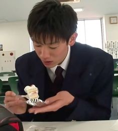 a young man in a suit eating a piece of cake