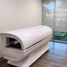 a large white object sitting on top of a hard wood floor next to a window