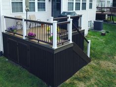 a deck with chairs and umbrellas in front of a house