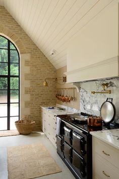 a kitchen with an arched window and marble counter tops, along with a rug on the floor