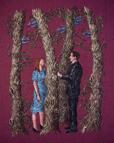 two people standing in front of trees with one holding the other's hand and looking at each other