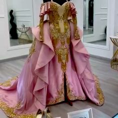 a pink and gold gown is on display in a room with other items around it