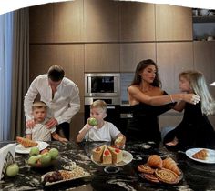 a woman and two children are standing in front of a table with food on it