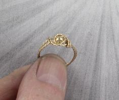 a person holding a ring in their hand on the beach with sand around them and waves behind it