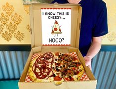 a man standing in front of a pizza box that says i know this is cheesy