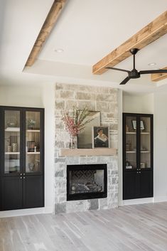 an empty living room with a fireplace and built - in bookcases