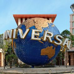 a large blue and gold globe with the word universal in it's center surrounded by buildings