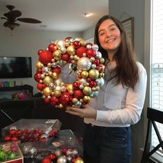 a woman holding a christmas wreath with ornaments on it