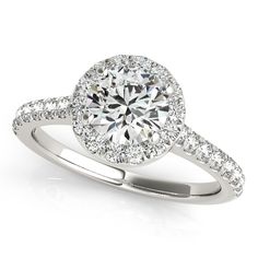 a white gold engagement ring with diamonds on the band and an oval halo setting in the center