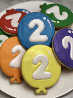 decorated cookies on a plate with the numbers two and three in different colors are shown