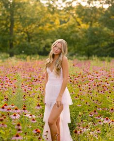 a woman in a white dress standing in a field full of flowers