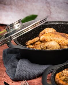 a pan filled with chicken sitting on top of a table next to a knife and fork