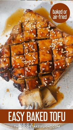 baked tofu with sesame seeds on top and brown sauce in the middle, sitting on a white plate