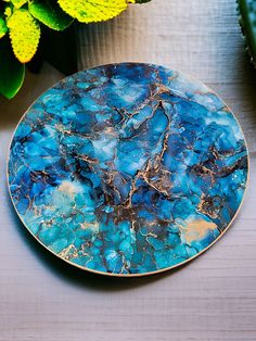 a blue plate sitting on top of a wooden table next to yellow and green flowers