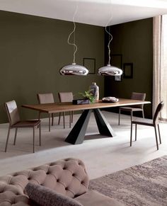 a dining room table with chairs and lights hanging from it's ceiling, in front of a window