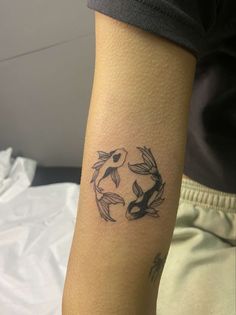 a person with a tattoo on their arm that has two koi fish in it