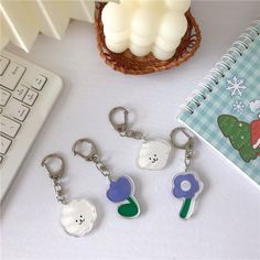 four keychains with cartoon characters on them sitting next to a keyboard and mouse