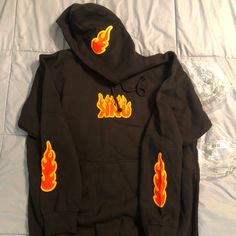 Fanjoy Knj Flame Hoodie In Black And Size Large. Item Was Not Used, But Is Outside Of Packaging And Has Slight Defect On The Flame That’s On The Hood. Please Review Photos And Ask Any Questions You Have Before Purchasing. Casual Black Hoodie For Halloween, Orange Long Sleeve Hoodie For Winter, Casual Halloween Sweatshirt For Streetwear, Trendy Orange Hoodie For Winter, Orange Hoodie Sweatshirt For Winter, Orange Letter Print Sweatshirt For Winter, Casual Orange Hoodie Outerwear, Orange Winter Top With Drawstring Hood, Casual Halloween Streetwear Hoodie