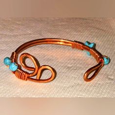 a copper cuff with turquoise beads on it and an open loop around the clasps