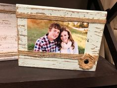 an old wooden frame with a couple's photo on it, sitting on a table