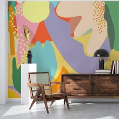 an abstract painting on the wall next to a chair and sideboard with a lamp