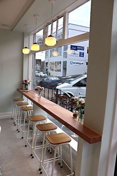 an empty restaurant with stools and tables in front of large windows looking out onto the street