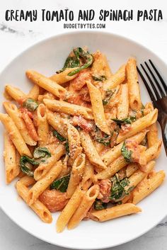 a white bowl filled with pasta and spinach