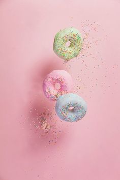 three donuts with sprinkles on a pink background - stock photo - images