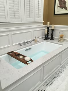 a bathroom with a large bathtub next to two candles and pictures on the wall