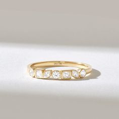 a yellow gold ring with five stones on the side, set against a white background