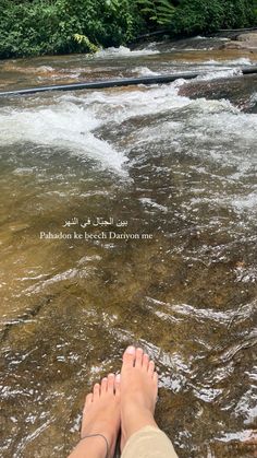 someone is standing in shallow water with their feet up on the edge of the river