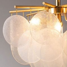 four white glass plates hanging from a brass chandelier with gold fittings on it