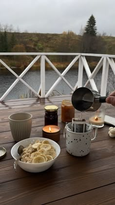 a wooden table topped with bowls filled with food next to candles and saucers on top of it