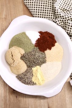 a white bowl filled with spices on top of a wooden table