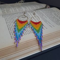 a pair of colorful beaded earrings sitting on top of an open book