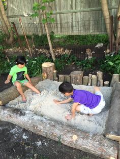 two young boys playing in the sand outside