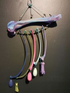 several different colored necklaces hanging from a hook on a gray wall in a room