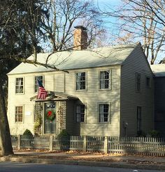 an old house with a wreath on the front door and american flag hanging from it's roof