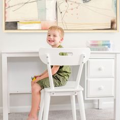 a little boy sitting in a white chair