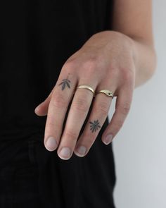 a person wearing a gold ring with an arrow tattoo on their left hand and the other finger