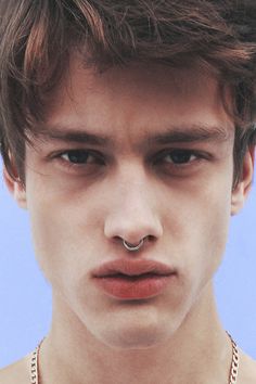 a young man wearing a necklace and nose piercing