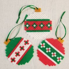 three christmas ornament ornaments hanging on a white tablecloth with green and red trim