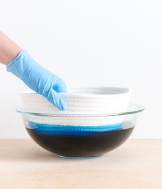 a person in blue gloves is washing a bowl with black and white cloth on it