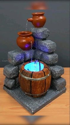 a fountain made out of rocks with water coming from it and two pots on top